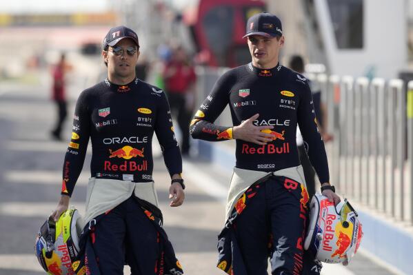 Max Verstappen (derecha) y Sergio Pérez, pilotos de Red Bull, llegan para participar en las pruebas de pretemporada de la Fórmula en el circuito de Sakhir, Bahréin, el jueves 23 de febrero de 2023. (AP Foto/Frank Augstein)