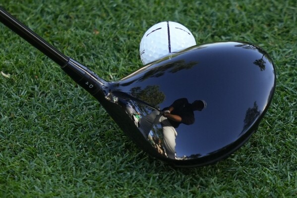 Tom Kim, of South Korea, is reflected in his driver on the 18th hole during weather delayed first round at the Masters golf tournament at Augusta National Golf Club Friday, April 12, 2024, in Augusta, Ga. (AP Photo/Matt Slocum)