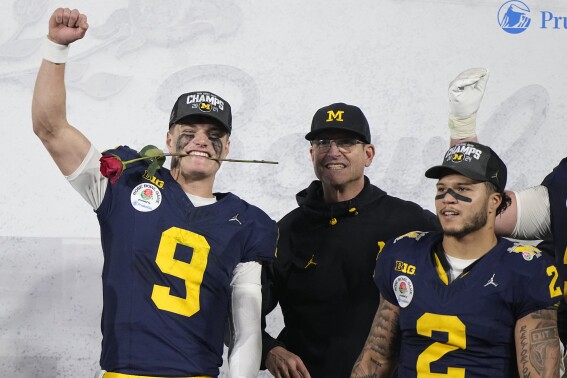 FILE - Michigan quarterback J.J. McCarthy (9), head coach Jim Harbaugh and running back Blake Corum (2) celebrate on the podium after a win over Alabama in the Rose Bowl CFP NCAA semifinal college football game Monday, Jan. 1, 2024, in Pasadena, Calif. J.J. McCarthy is expected to be the first of many drafted from Michigan’s national championship-winning team. The Wolverines had a record 18 players at the combine. If Jim Harbaugh’s last team has 16 or more players drafted, they will surpass another former champion, Georgia’s 2022 team, that had 15 players selected. (AP Photo/Mark J. Terrill, File)