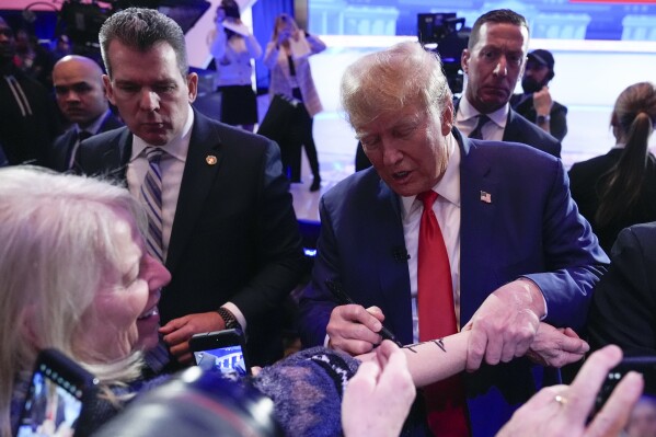 Republican presidential candidate former President Donald Trump signs an autograph on a woman's arm as he greets members of the audience after a Fox News Channel town hall in Des Moines, Iowa, Wednesday. (AP Photo/Carolyn Kaster)
