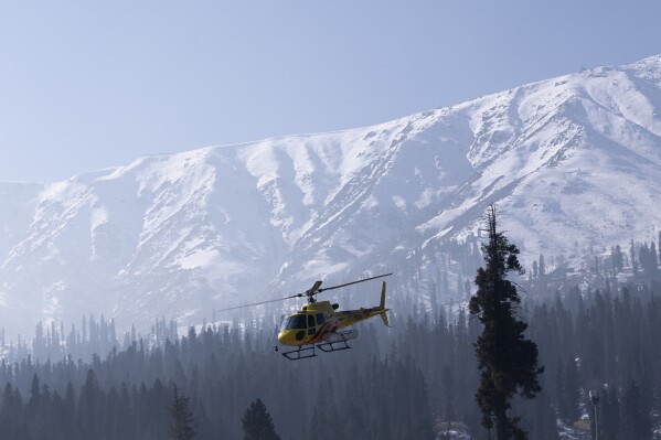Tourists enjoy a helicopter ride in Gulmarg, northwest of Srinagar, Indian controlled Kashmir, Saturday, Jan. 13, 2024. These helicopters were used for heliskiing, but due to a lack of snow, the owner has decided to offer joy rides to tourists to compensate for losses. (AP Photo/Dar Yasin)