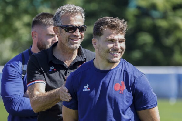 France's rugby head coach Fabien Galthie, left, and France's Antoine Dupont smile during a gathering with France's President Emmanuel Macron at their base camp's training center in Rueil-Malmaison, outside Paris, Monday, Sept. 4, 2023, ahead of the France 2023 Rugby World Cup. (Ludovic Marin, Pool via AP)