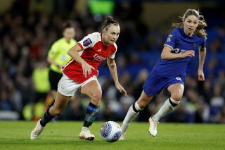 Arsenal's Caitlin Foord, left, and Chelsea's Melanie Leupolz battle for the ball during the Women's Super League soccer match between Chelsea and Arsenal at Stamford Bridge, London, Friday March 15, 2024. (Nigel French/PA via AP)