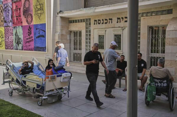 Patients rest outdoors after a building of the Soroka hospital complex was hit by a missile fired from Iran in Beersheba, Israel, Thursday, June 19, 2025. (AP Photo/Leo Correa)