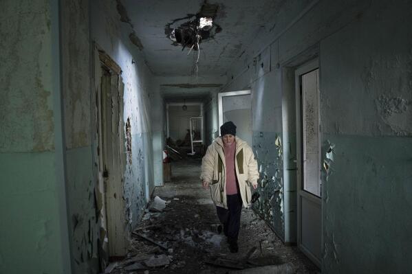 Valentyna Mozgova, 55, a lab medic walks in the corridor of a hospital which was damaged by Russian shelling in Krasnohorivka, Ukraine, Sunday, Feb. 19, 2023. A year into Russia's war in Ukraine, researchers have documented more than 700 attacks against health care facilities and staff. The data was verified by five organizations working in Ukraine and released Tuesday. (AP Photo/Evgeniy Maloletka)