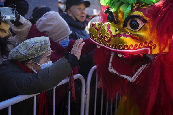 A woman touches the lion dance as residents watch traditional artists performance at the Dongyue Temple on the first day of the Chinese Lunar New Year in Beijing, Saturday, Feb. 10, 2024. (APPhoto/Andy Wong)