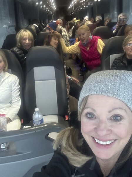 In this photo provided by Brenda Djorup, Djorup takes a photo of herself and other women who were stranded on a Thera-ski bus on Interstate 70 in Colorado on the way back from a ski trip to Vail, Colo., Wednesday, March 13, 2024. The women spent 22 hours on the bus getting back from the ski hill after getting stuck behind semi tractor-trailers. (Brenda Djorup via AP)