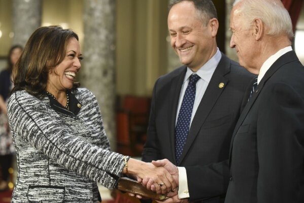 FILE - In this Jan. 3, 2017, file photo, then-Vice President Joe Biden, right, shakes hands with Sen. Kamala Harris, D-Calif., as her husband Douglas Emhoff, watches during a a mock swearing in ceremony in the Old Senate Chamber on Capitol Hill in Washington. Most of the two dozen White House hopefuls have pre-existing friendships from their time on Capitol Hill or other Democratic circles. But few are as complex _ and potentially awkward _ as the tie between Harris and Biden.  (AP Photo/Kevin Wolf, File)