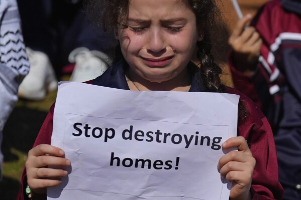A girl weeps as she holds a placard during a protest against Israel's attack on the Gaza Strip, in front of the headquarters of U.N. Economic and Social Commission for Western Asia (ESCWA) in Beirut, Lebanon, Tuesday, Nov. 21, 2023. An Israeli strike on southern Lebanon killed Tuesday two journalists reporting for the Beirut-based Al-Mayadeen TV on the violence along the border with Israel, according to the Lebanese information minister and their TV station. (AP Photo/Bilal Hussein)