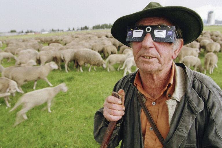 FILE - Shepherd Heinz Greiner watches the beginning of a total solar eclipse near Augsburg, southern Germany, on Wednesday, Aug. 11, 1999. A German myth has the cold and lazy male moon, ignoring the fiery passionate female sun during the day most of the time, except for a few bits of passion during an eclipse and then they'd squabble again and the sun would resume shining again, Mark Littmann of the University of Tennessee says. (AP Photo/Frank Boxler, File)