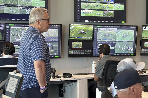 Alberto Riveron, left, the Atlantic Coast Conference supervisor of football officials, works in the league’s new tech-heavy gameday center — roughly four times larger than the previous setup — in the league's new headquarters in a downtown tower overlooking the stadium home of the NFL's Carolina Panthers in Charlotte, N.C.,Saturday, Sept. 2, 2023. (AP Photo/Aaron Beard)