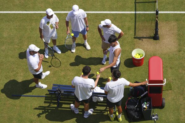Carlos Alcaraz of Spain stands with his team during a training session at the Queen's Club Tennis Championships in London, England, Thursday, June 19, 2025. (AP Photo/Kirsty Wigglesworth)