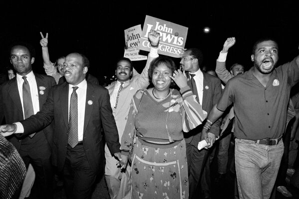 FILE - In this Tuesday night, Sept. 3, 1986, file photo, John Lewis, front left, and his wife, Lillian, holding hands, lead a march of supporters from his campaign headquarters to an Atlanta hotel for a victory party after he defeated Julian Bond in a runoff election for Georgia's 5th Congressional District seat in Atlanta. Lewis, who carried the struggle against racial discrimination from Southern battlegrounds of the 1960s to the halls of Congress, died Friday, July 17, 2020. (AP Photo/Linda Schaeffer, File)