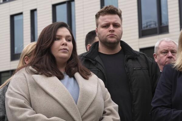 Ellie and Harry Baxter, the son and daughter of Stephen, 61, and Carol, 64, Baxter, stand outside Chelmsford Crown Court, in Chelmsford, England, Friday March 22, 2024 as a statement is read by the police after the sentencing of Luke D'Wit. D'Wit, a British IT worker who befriended and worked for Stephen and Carol Baxter, poisoned them with fentanyl and monitored their death with his cell phone was sentenced Friday to a minimum 37 years in prison. (Stefan Rousseau/PA via AP)