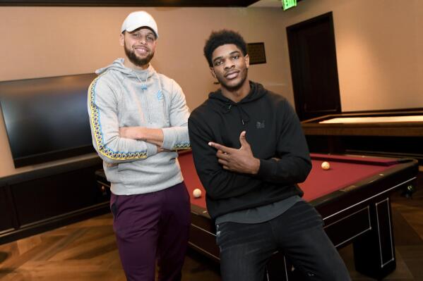 In a photo provided by SC30, Golden State Warriors' Stephen Curry, left, poses for photos with Scoot Henderson, one of the NBA's top future prospects, Thursday, March 30, 2023, in San Francisco. Curry has formed the strategic alliance to help Henderson build his business model and will offer his resources to the rising star and his family as the guard makes the transition to the next level after spending two seasons with the G League Ignite to establish himself as a projected top-three draft pick. (Noah Graham/SC30 via AP)
