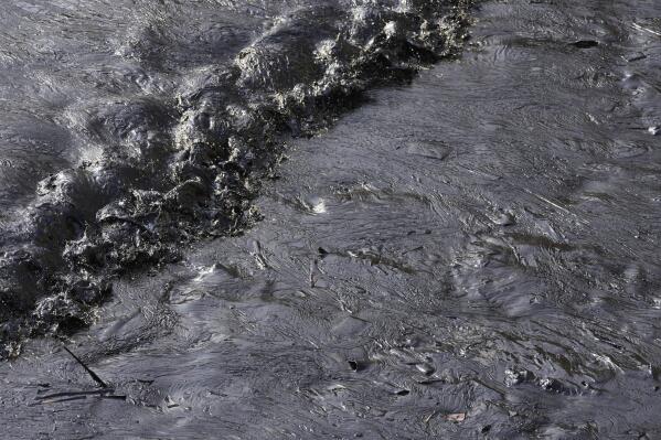 Oil from a spill covers the shore at Cavero beach in Ventanilla, Callao, Peru, Monday, Jan. 17, 2022. Unusually high waves that authorities attribute to the eruption of the undersea volcano in Tonga caused the spill on the Peruvian Pacific coast as a ship was loading oil into La Pampilla refinery on Sunday. (AP Photo/Martin Mejia)