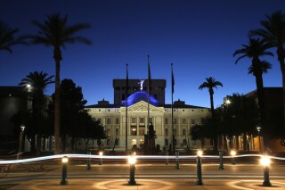 FILE - The blur of car lights zip past the Arizona Capitol as the dome is illuminated on April 15, 2020, in Phoenix. Social media users are falsely suggesting Arizona lawmakers have brought criminal charges against the state’s sitting governor. But no such indictment has been issued, and the state legislature isn’t authorized to issue such formal accusations of criminal wrongdoing in the first place. (AP Photo/Ross D. Franklin, File)