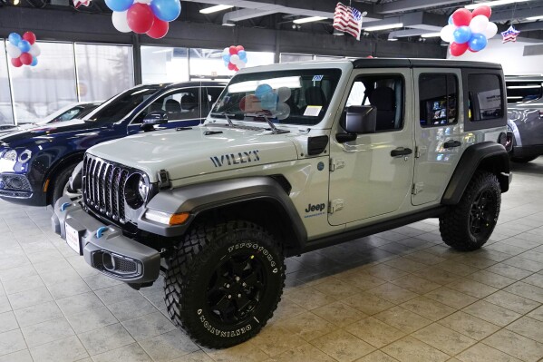 File - A plug-in hybrid gas/electric Jeep Wrangler is displayed on the showroom floor at the Dan O'Brien Auto Group dealership, Monday, Feb. 27, 2023, in Methuen, Mass. Stellantis says it is pulling together a network of public electric vehicle chargers that could include could include Tesla and nearly all of the other chargers in the U.S., Canada and Europe. (AP Photo/Charles Krupa, File)