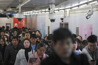 FILE - In this Feb. 26, 2019, file photo commuters walk by surveillance cameras installed at a walkway in between two subway stations in Beijing. The Carnegie Endowment for International Peace released a report Tuesday, Sept. 17, that found at least 75 countries are actively using AI tools such as facial recognition for surveillance. The new report says a growing number of countries are following China’s lead in deploying artificial intelligence to track citizens. (AP Photo/Andy Wong, File)