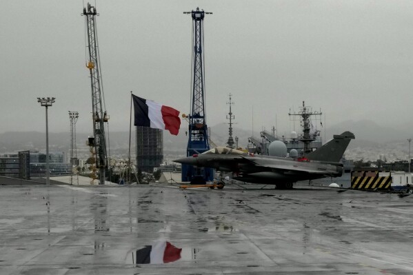 A Rafale jet fighter next to a French flag, on France's nuclear-powered aircraft carrier Charles de Gaulle, at Limassol port, Cyprus, Tuesday, March 1, 2022. AP Photo/Petros Karadjias, File)
