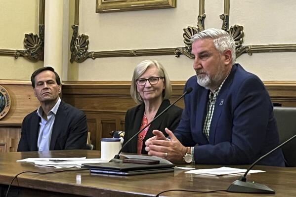 Indiana Gov. Eric Holcomb, right, speaks during a news conference alongside State Health Commissioner Dr. Kristina Box, center, and state Commerce Secretary Brad Chambers at the governor's Statehouse office in Indianapolis on Friday, April 28, 2023. Holcomb said he would gladly sign the new state budget agreement approved by legislators after several messy hours of negotiations on Thursday. (AP Photo/Tom Davies)