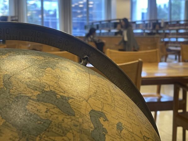 People talk quietly in the U.N. library while an old globe sits in the foreground on Friday, Sept. 22, 2023, at United Nations headquarters. The library is one of several areas in the U.N. compound where people whose job is to handle the problems and challenges of the world can relax for a few minutes. (AP Photo/Ted Anthony)