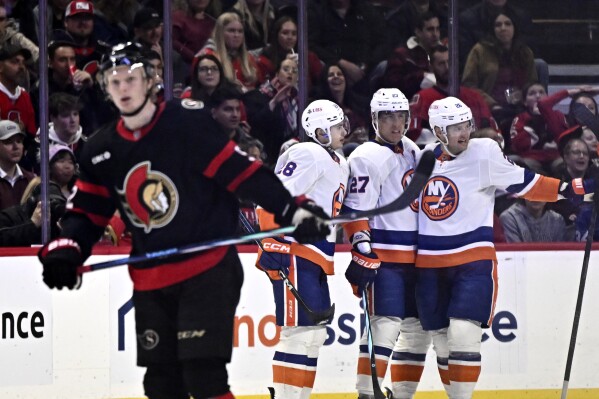 New York Islanders right wing Oliver Wahlstrom (26) celebrates after his goal with defenseman Alexander Romanov (28) and left wing Anders Lee (27) as Ottawa Senators left wing Roby Jarventie (52) skates away during second-period NHL hockey game action in Ottawa, Ontario, Friday, Nov. 24, 2023. (Justin Tang/The Canadian Press via AP)