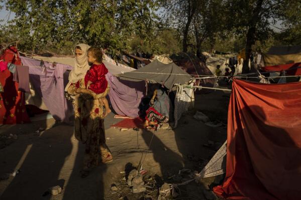 An internally displaced woman holds a child at an internally displaced camp in Kabul, Afghanistan, Monday, Sept. 13, 2021. A month after the fall of Kabul, the question of how the world will get aid to citizens without enriching Afghanistan's Taliban rulers is haunting the country. The stakes have soared for Afghans, who along with the threat of famine and a collapsing health care system face a looming crisis as winter approaches. (AP Photo/Bernat Armangue)