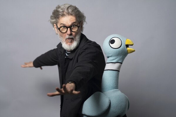 Author Mo Willems poses with The Pigeon, a character in his children's books, on April 22, 2025, in New York. (AP Photo/Gary Gerard Hamilton)
