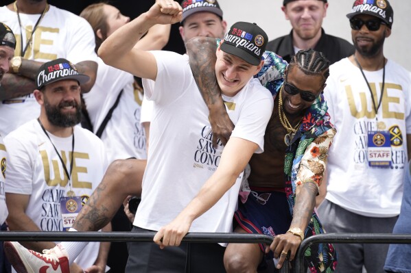 Denver Nuggets center Nikola Jokic, center left, jokes with guard Kentavious Caldwell-Pope, center right, during a rally and parade to mark the team's first NBA basketball championship on Thursday, June 15, 2023, in Denver. (AP Photo/David Zalubowski)