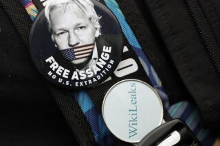 Badges worn by a demonstrator outside Westminster Magistrates Court in London, Wednesday, Feb. 19, 2020. A case-management hearing regarding Julian Assange will be heard at the court Wednesday. It comes just five days before the extradition hearing beginning Feb. 24, at Woolwich Crown Court, in which both Julian Assange and the broader issues of press freedom will be at stake. (AP Photo/Kirsty Wigglesworth)