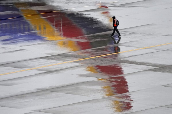 FILE - A ground operations crew member walks past a Southwest Airlines jet sitting at a gate, Dec. 28, 2022, at Sky Harbor International Airport in Phoenix. The federal government may be preparing to penalize Southwest Airlines for thousands of flight cancellations that affected more than 2 million travelers last December. Southwest disclosed the potential fine on Monday, Oct. 30, 2023 and said it couldn't estimate how large it might be. (AP Photo/Matt York, File)