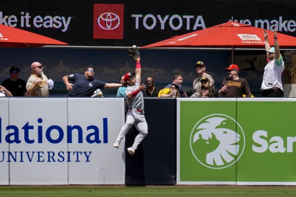 Cincinnati Reds center fielder Stuart Fairchild makes a leaping catch over the wall for the out on San Diego Padres' Manny Machado during the first inning of a baseball game, Wednesday, May 1, 2024, in San Diego. (AP Photo/Gregory Bull)