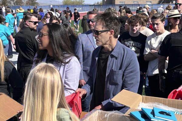 In this photo provided by Jesse Sorenson, actor Kevin Bacon, center, helps fill care packages for his charity, Saturday, April 20, 2024, in Payson, Utah, while visiting the Utah high school where cult classic "Footloose," was filmed. (Jesse Sorenson via AP)