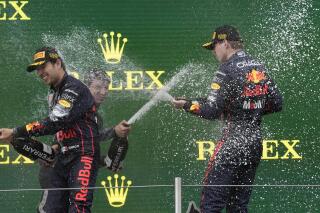 Los pilotos de Red Bull, Max Verstappen (derecha) y Sergio Pérez celebran en el podio luego de ganar el 1er y 2do lugar respectivamente en el Gran Premio de Emilia Romaña, el domingo 24 de abril de 2022, en Imola, Italia. (AP Foto/Luca Bruno)