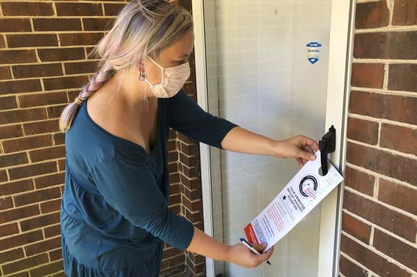 Christin Clatterbuck leaves an affidavit and information about fixing absentee ballots on the door of a home in Stone Mountain, Ga., Friday, Nov. 6, 2020. (AP Photo/Sudhin Thanawala)