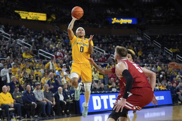 Michigan Wolverines guard Dug McDaniel (0) drives on Wisconsin forward Tyler Wahl (5) in the second half of an NCAA college basketball game in Ann Arbor, Mich., Wednesday, Feb. 7, 2024. (AP Photo/Paul Sancya)