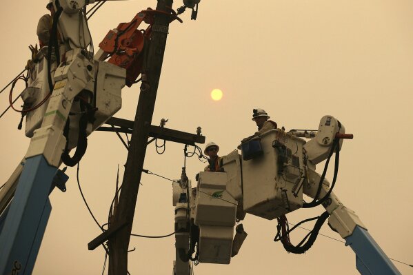 
              FILE - In this Nov. 9, 2018 file photo, Pacific Gas & Electric crews work to restore power lines in Paradise, Calif. Some investors call PG&E the first climate change bankruptcy. It filed for Chapter 11 protection earlier this year due to potential liabilities piling up following devastating wildfires in northern California. (AP Photo/Rich Pedroncelli, File)
            
