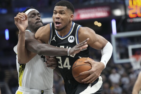 Milwaukee Bucks forward Giannis Antetokounmpo, right, goes around Indiana Pacers forward Pascal Siakam (43) during the first half of an NBA basketball game in Indianapolis, Tuesday, Dec. 31, 2024. (AP Photo/AJ Mast)