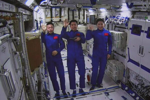 In this photo released by Xinhua News Agency, an image taken off the screen at the Beijing Aerospace Control Center shows Chinese astronauts from left, Cai Xuzhe, Chen Dong and Liu Yang wave from inside the Wentian lab module on Monday, July 25, 2022. China added the laboratory to its permanent orbiting space station Monday as it moves toward completing the structure in coming months. (Guo Zhongzheng/Xinhua via AP)