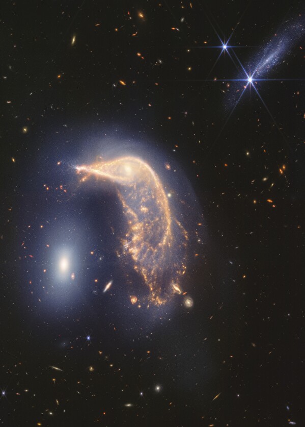 In this photo provided by NASA and the Space Telescope Science Institute, two interacting galaxies are captured by the Webb Space Telescope in the infrared. Scientists say the neighboring galaxies, nicknamed Penguin, right, and the Egg, left, have been tangled up for tens of millions of years. (NASA and Space Telescope Science Institute via AP)