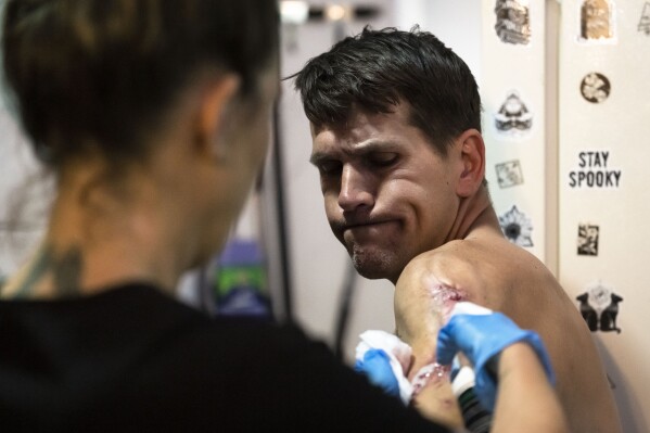Nick Gallagher reacts as volunteer registered nurse Jennifer D'Angelo treats his skin wounds the Savage Sisters' community outreach storefront in the Kensington neighborhood of Philadelphia, Wednesday, May 24, 2023. Xylazine can cause severe skin wounds, but whether it is leading to more deaths — as suggested by officials in Washington — is not yet clear, according to health and law enforcement professionals on the front lines of efforts in New Jersey, New York and Pennsylvania. (AP Photo/Matt Rourke)