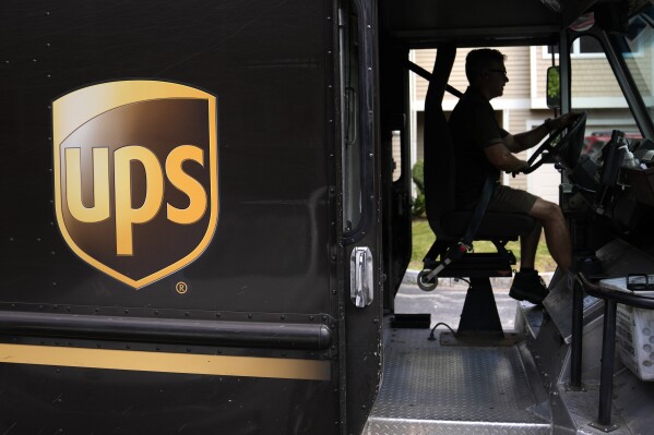 FILE - United Parcel Service driver Hudson de Almeida steers through a neighborhood while delivering packages, June 30, 2023, in Haverhill, Mass. The union representing 340,000 UPS workers said Tuesday, Aug. 22, that its members voted to approve the tentative contract agreement reached last month, putting a final seal on contentious labor negotiations that threatened to disrupt package deliveries for millions of businesses and households nationwide. (AP Photo/Charles Krupa, File)