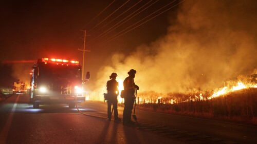 Firefighters monitor as flames consume brush along Gilman Springs Road during the Rabbit Fire late Friday, July 14, 2023, in Moreno Valley, Calif. (AP Photo/Eric Thayer)