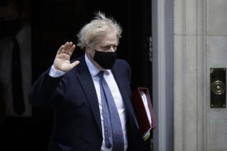 FILE - In this file photo dated Wednesday, May 19, 2021, wearing a face covering British Prime Minister Boris Johnson waves at the media as he leaves 10 Downing Street in London. An independent report Tuesday May 25, 2021, says British Prime Minister Boris Johnson helped create an impression that his Conservative Party is “insensitive” to Muslims.(AP Photo/Matt Dunham, FILE)
