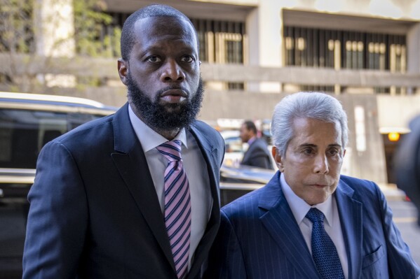 FILE - Prakazrel "Pras" Michel, left, a member of the 1990s hip-hop group the Fugees, accompanied by defense lawyer David Kenner, right, arrives at federal court for his trial March 30, 2023, in Washington. Michel argued this week that use of the generative AI program was one of a number of errors his previous attorney made a trial for which he was "unqualified, unprepared and ineffectual," according to a motion for new trial his new lawyers filed. (AP Photo/Andrew Harnik, File)