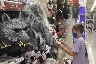 FILE - A young customer looks at a Halloween mask at a Party City store, Oct. 6, 2021, in Miami. Prices for U.S. consumers jumped 6.2% in October compared with a year earlier as surging costs for food, gas and housing left Americans grappling with the highest inflation rate since 1990. The year-over-year increase in the consumer price index exceeded the 5.4% rise in September, the Labor Department reported Wednesday, Nov, 10, 2021. (AP Photo/Marta Lavandier)