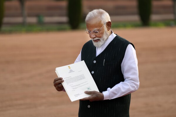 Indian Prime Minister Narendra Modi displays a letter from the President of India, Draupadi Murmu, inviting him to form the next central government, outside the Rashtrapati Bhavan in New Delhi, India, Friday, June 7, 2024. (AP Photo/Manish Swarup)
