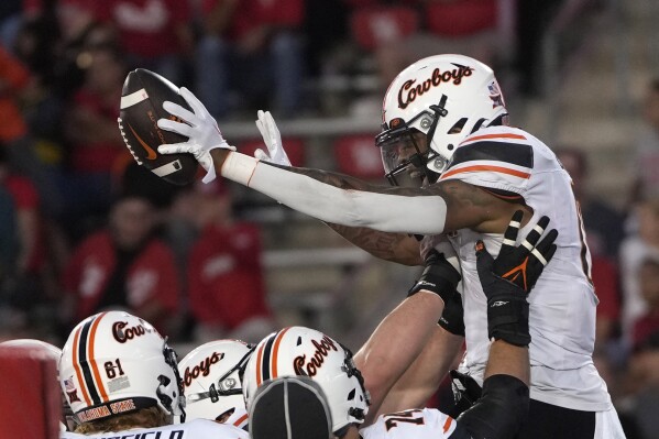 Oklahoma State running back Ollie Gordon II celebrates with teammates after scoring a touchdown against Houston during the second half of an NCAA college football game Saturday, Nov. 18, 2023, in Houston. Oklahoma State won 43-30. (AP Photo/David J. Phillip)