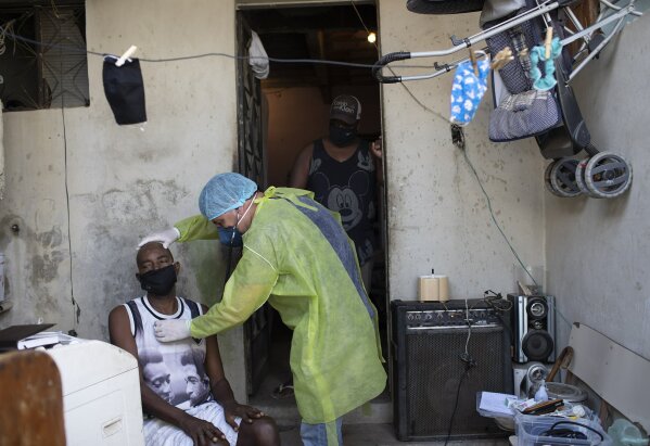 Dr. Wille Baracho checks on Mario de Santos, suspected of suffering COVID-19, at his home in the Vila Vintem favela in Rio de Janeiro, Brazil, Tuesday, May 19, 2020. Vila Vintem is home to more than 15,000 people. Its name reflects its undesirable location: when first settled, the swampy area was said to be worth not even a vintem – the cheapest coin at the time, akin to a penny.  (AP Photo/Silvia Izquierdo)